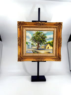 1984 signed oil on canvas Venezuelan street scene, framed — front view on the stand, wider shot
