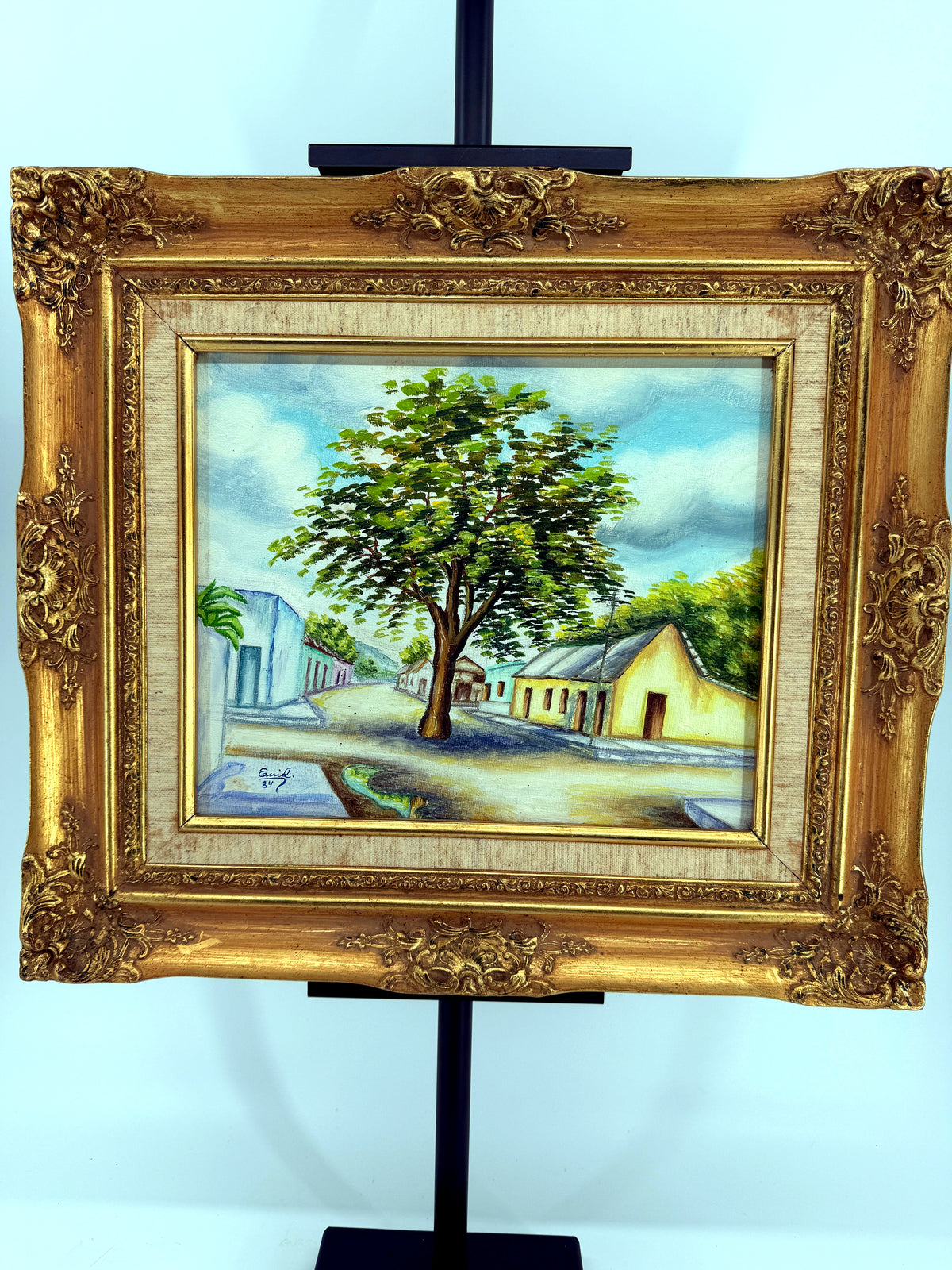 1984 signed oil on canvas Venezuelan street scene, framed — front view on the stand