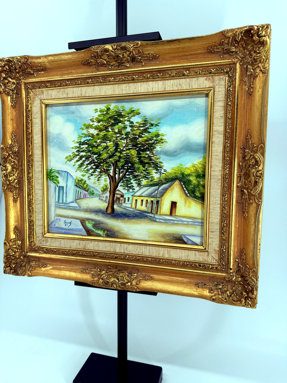 1984 signed oil on canvas Venezuelan street scene, framed — front view from a left angle