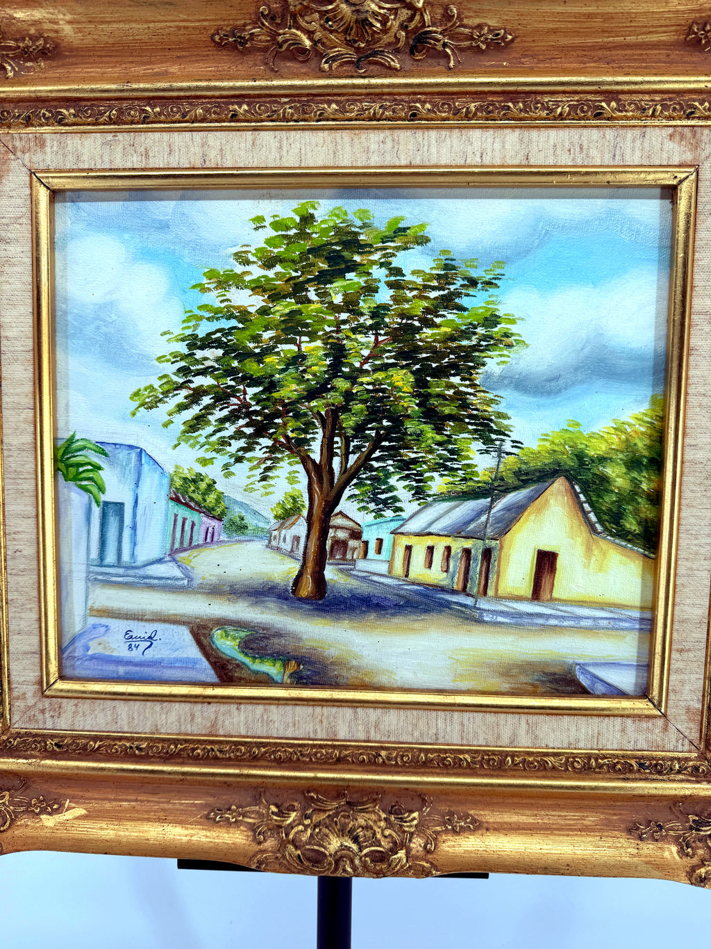 1984 signed oil on canvas Venezuelan street scene, framed — close-up of the painting — the tree and the yellow cottage